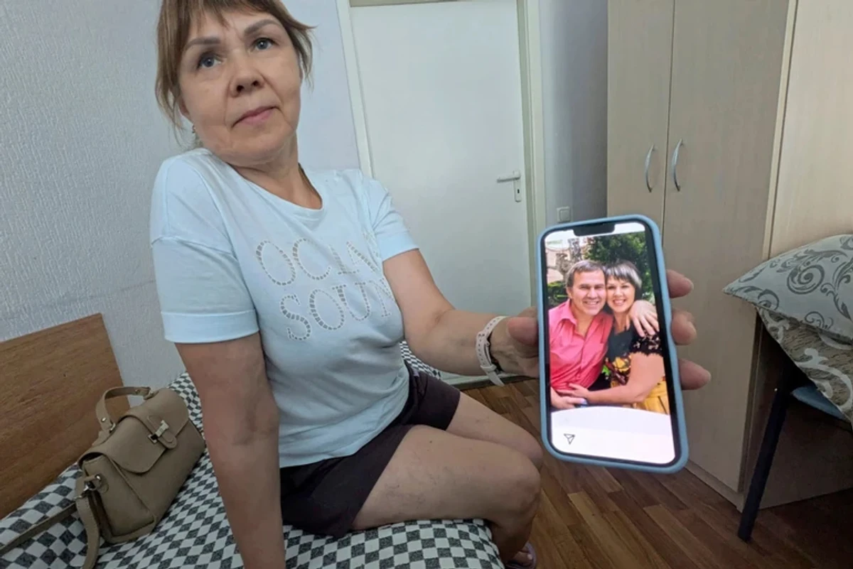 Oleh Kotov's wife shows a photo of her and her husband together