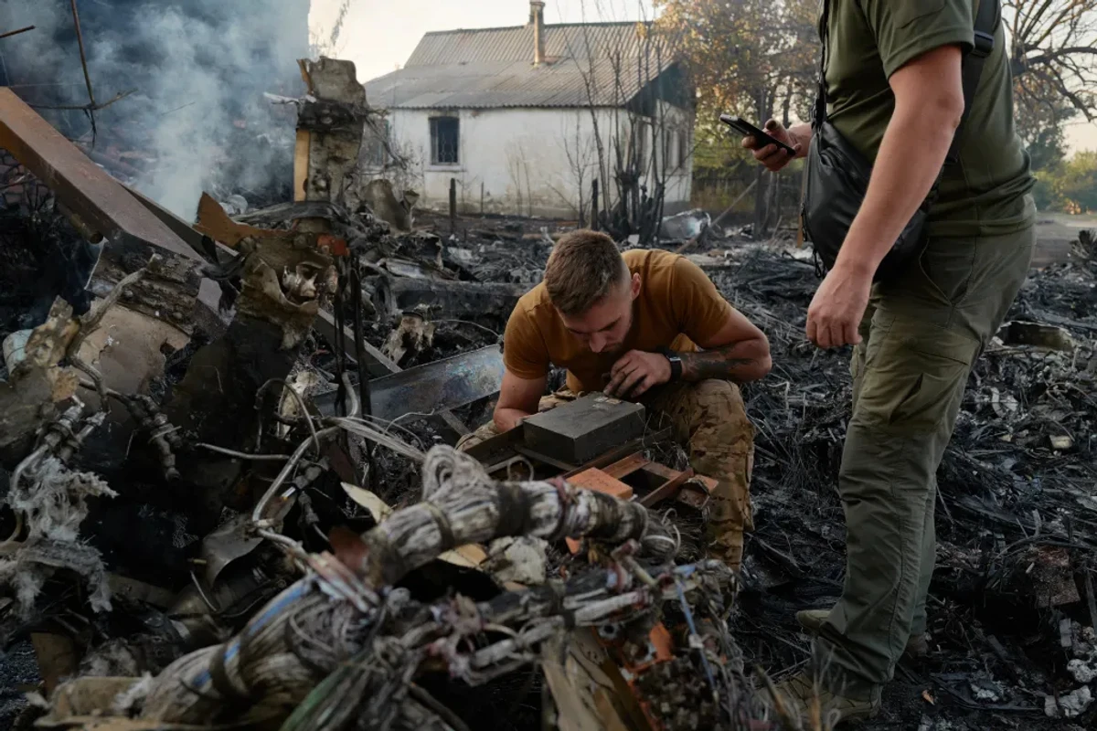 Ukrainian servicemen examine the wreckage of a Russian S-70 UAV.