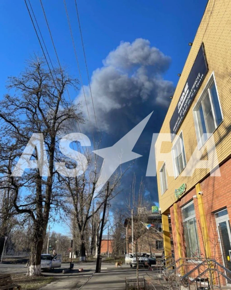 A thick plume of dark smoke rises into the sky