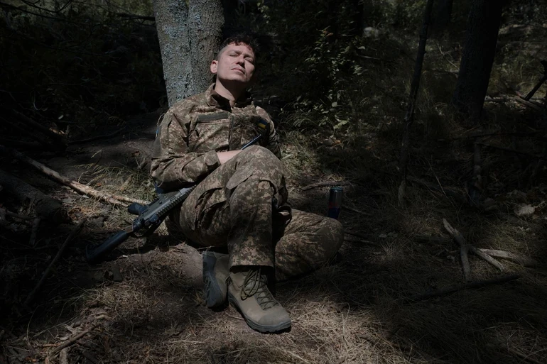A soldier sleeping under a tree.