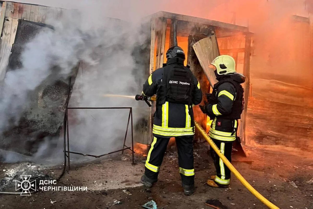 Two firefighters in protective gear tackle a blaze inside a damaged building
