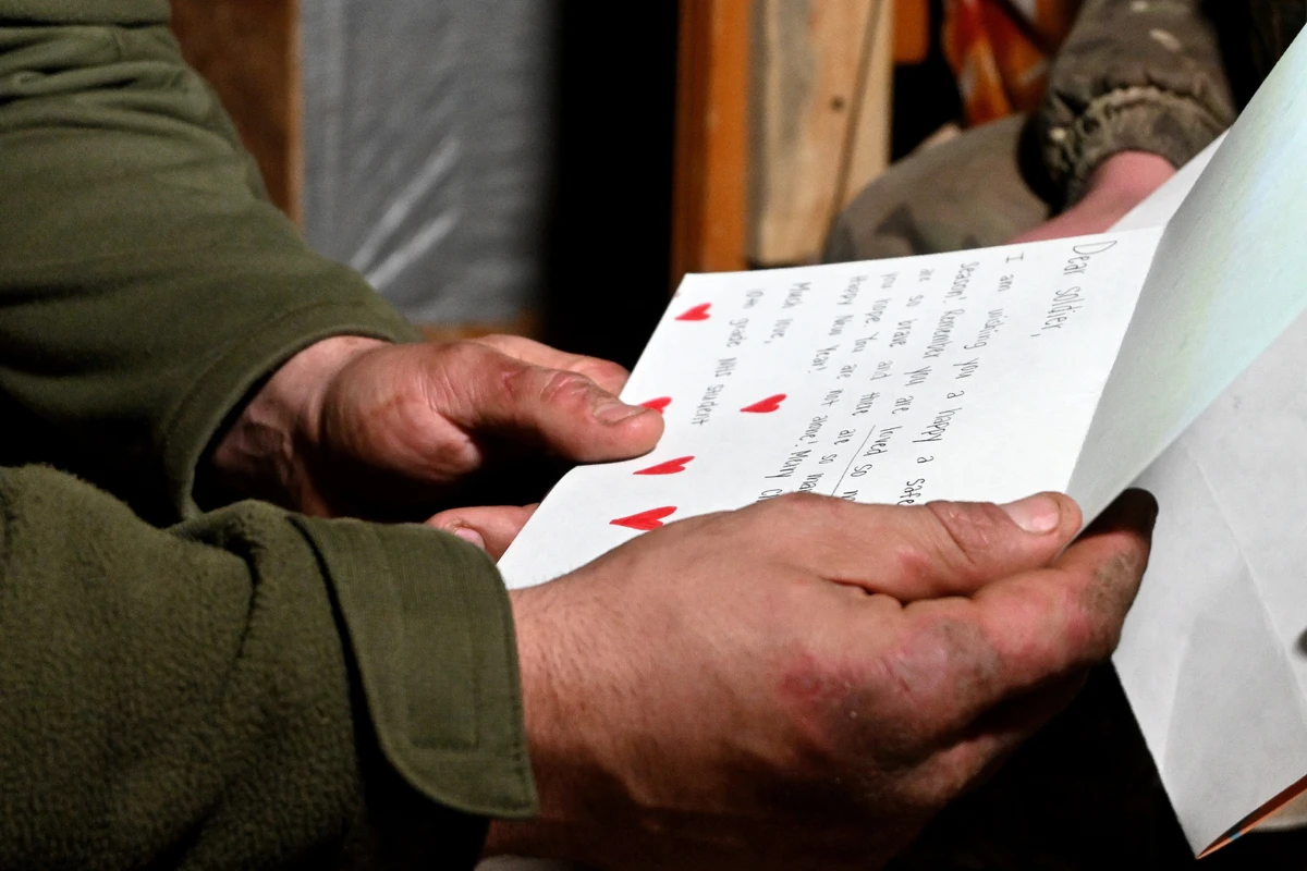 Ukrainian soldiers in a dugout read letters from American schoolchildren