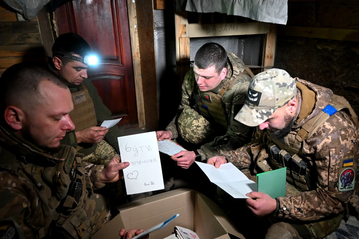 Ukrainian soldiers in a dugout read letters from American schoolchildren