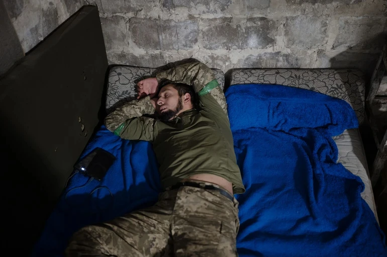 A soldier sleeping in a basement.
