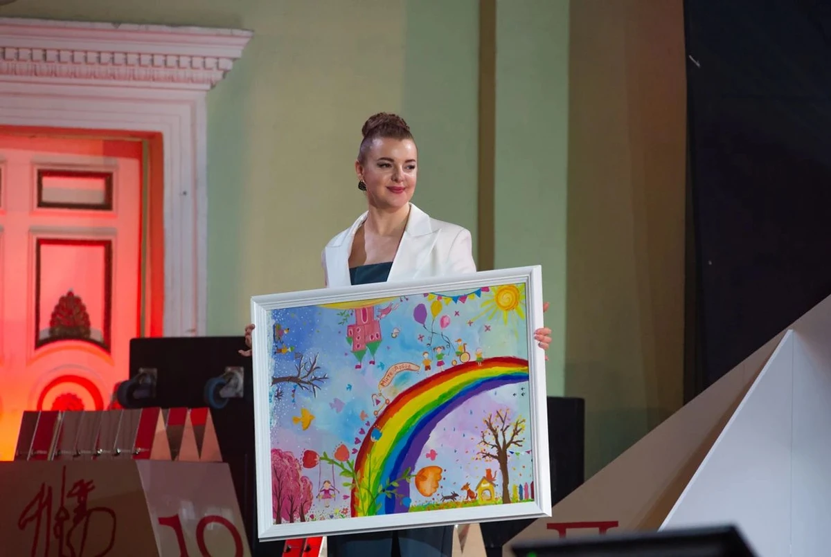 Viktoriia Zaichenko, Ukrainska Pravda's event director, holding the painting created by children from the City of Goodness