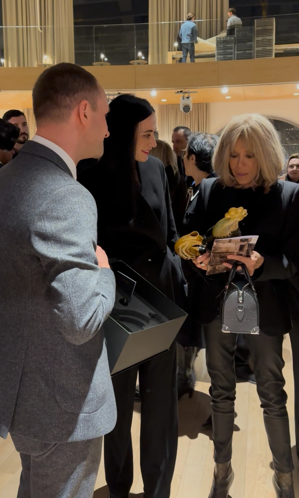 First Lady Brigitte Macron being presented with a cockerel