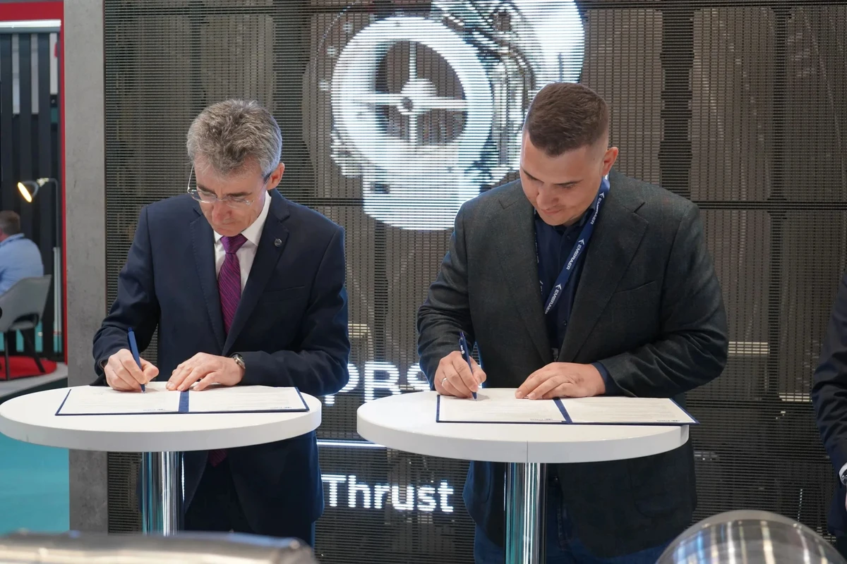 A representative of PBS Group (left) and Vitalii Kolesnichenko, CEO of Ukraine's Airlogix (right) are signing the memorandum of cooperation