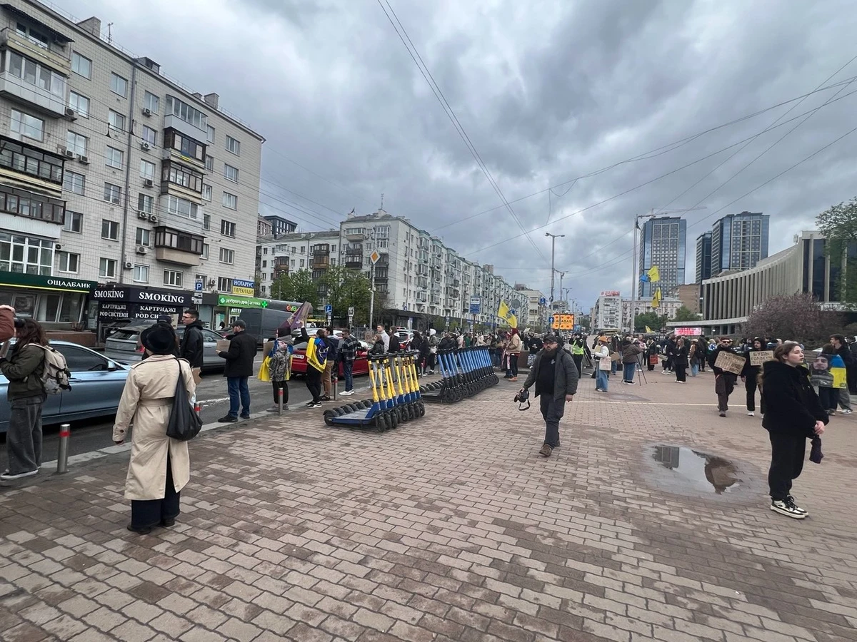 Дощ заважає людям провести подію біля палацу Україна. На площі їх небагато, вони постійно спускаються та підіймаються з підземного переходу