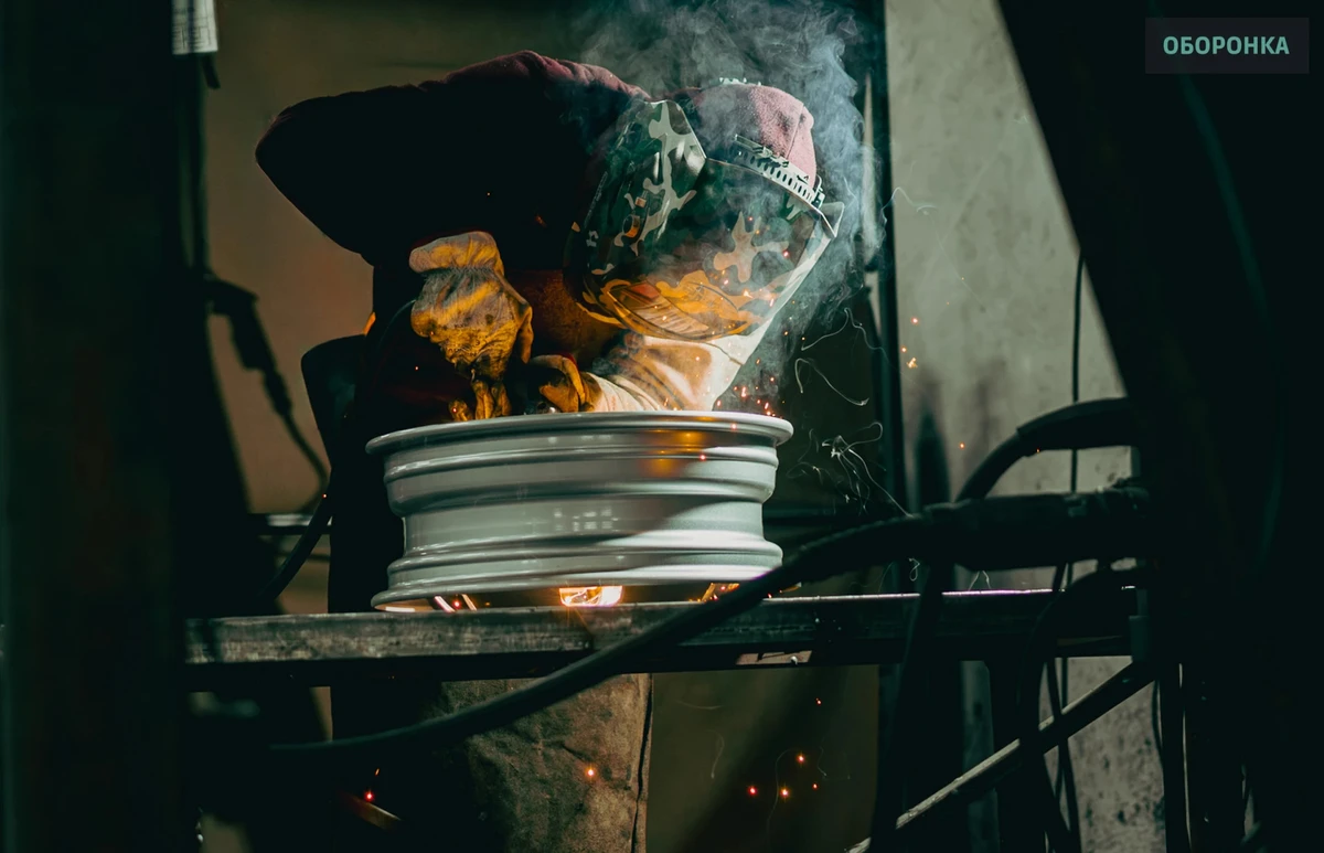 A welder working on a wheel rim