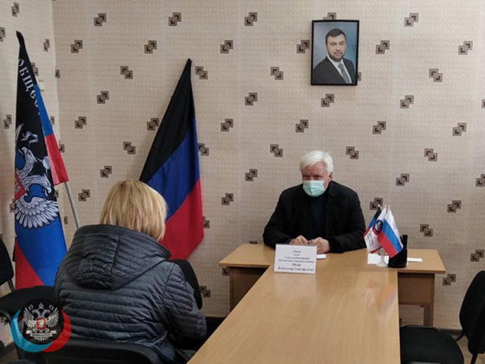 Володимир Меша проводить прийом громадян на тлі портеру бойовика Пушиліна та прапору угрупування “ДНР”