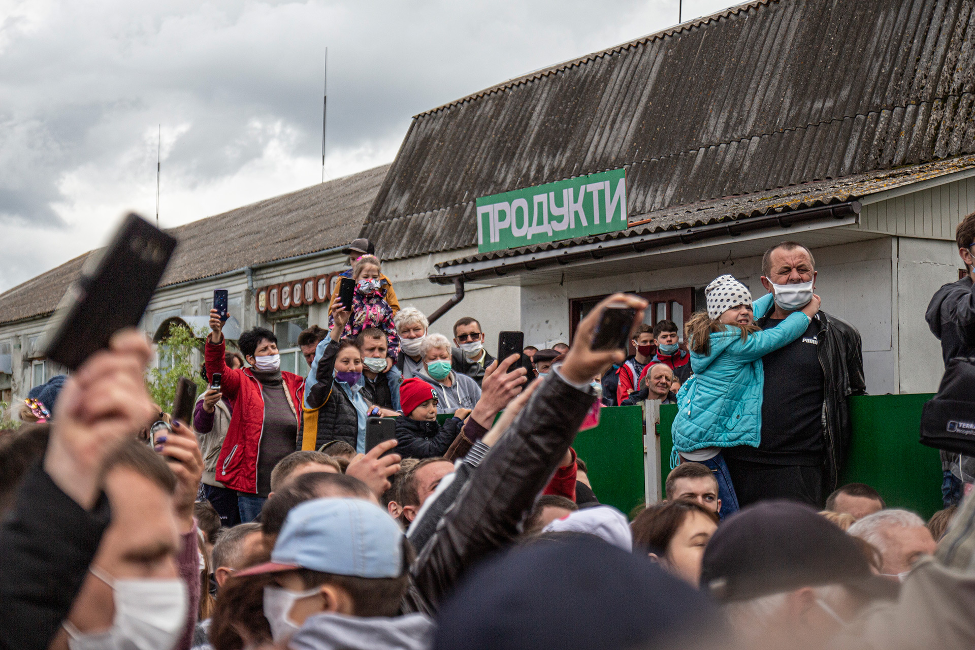 Люди собрались у продуктового магазина в окружении президентской охраны. Почти все – в масках