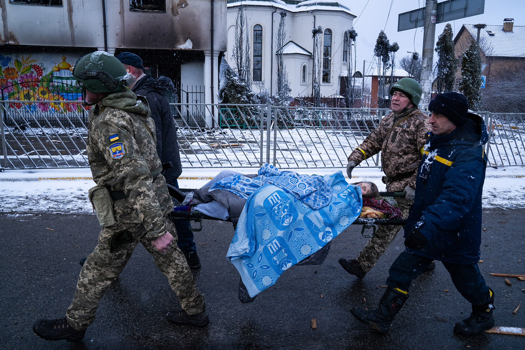 Солдати ЗСУ та працівникм ДСНС допомагають літній жінці евакуюватися з Ірпеня
