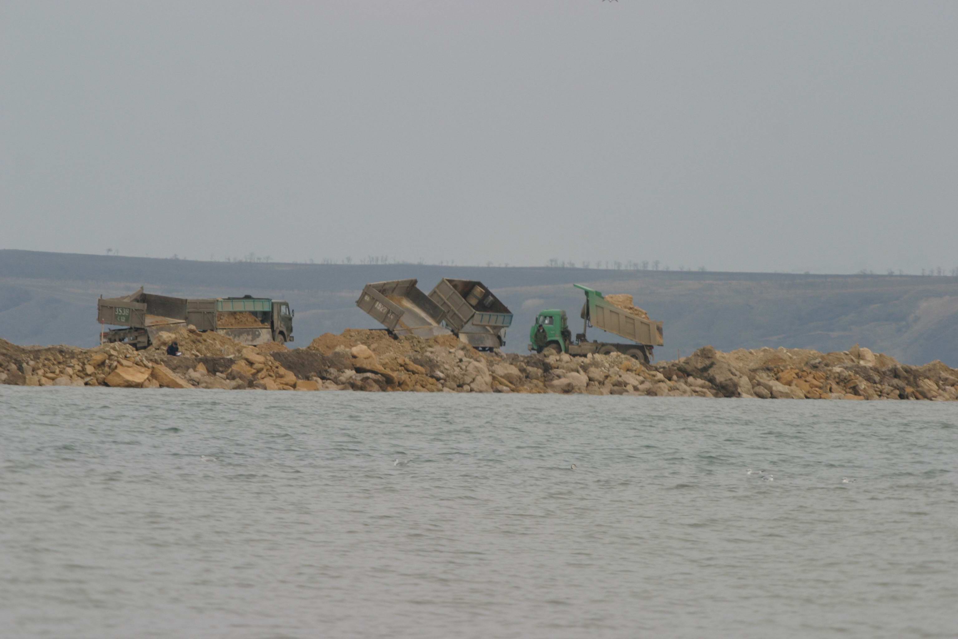 Михайло Коваль: На Тамані розгорнули кілька таборів з технікою. В першому великий парк вантажних автомобілів. В другому – екскаватори і бульдозери. Вони почали з кам'яних кар'єрів доставати грунт, грузити на машини і по мілині нарощувати дамбу в бік Тузли